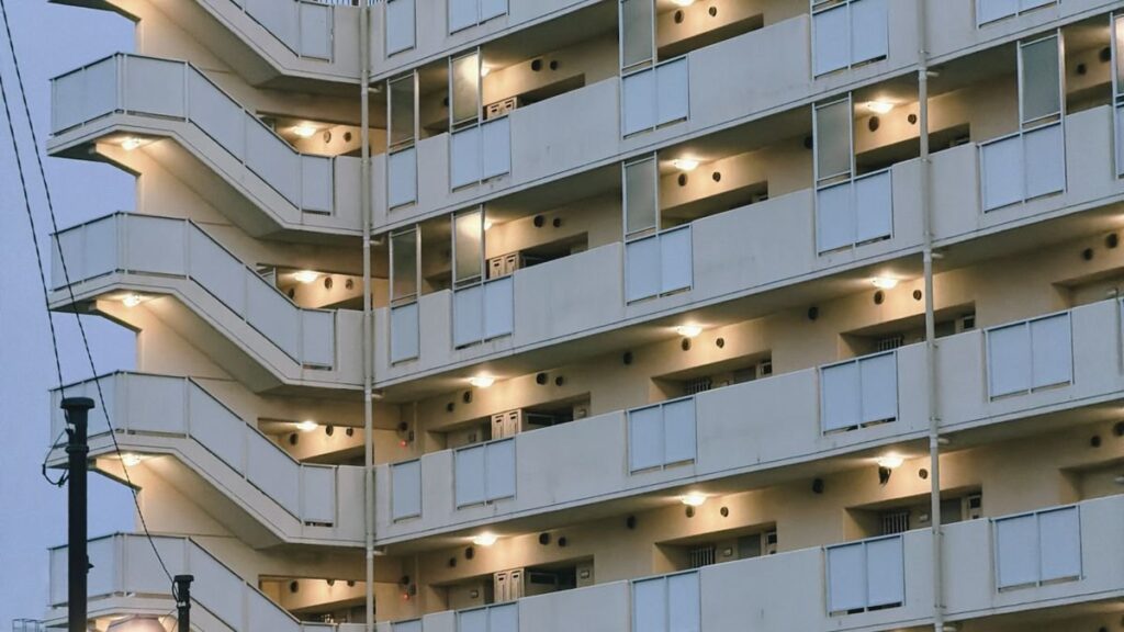 夕暮れに明かりがともる都心のマンションのイメージ